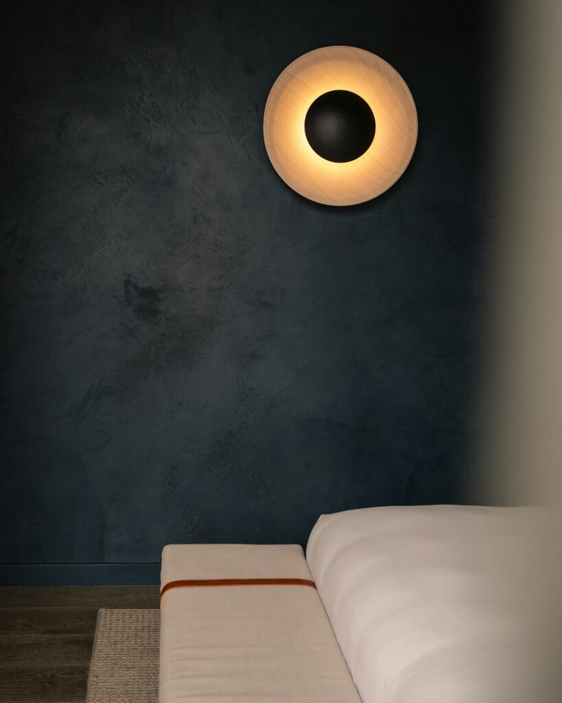 Aurora Hotels case study: circular wall light on a dark textured wall
